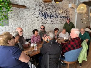 Photo from May 17th meeting of the WCBNY Coffee Club. Members are seen sitting around a table and chatting over coffee and snacks.